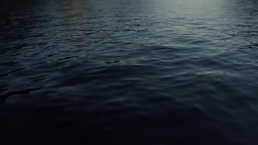 Water ripples softly with dark mountains in the distance