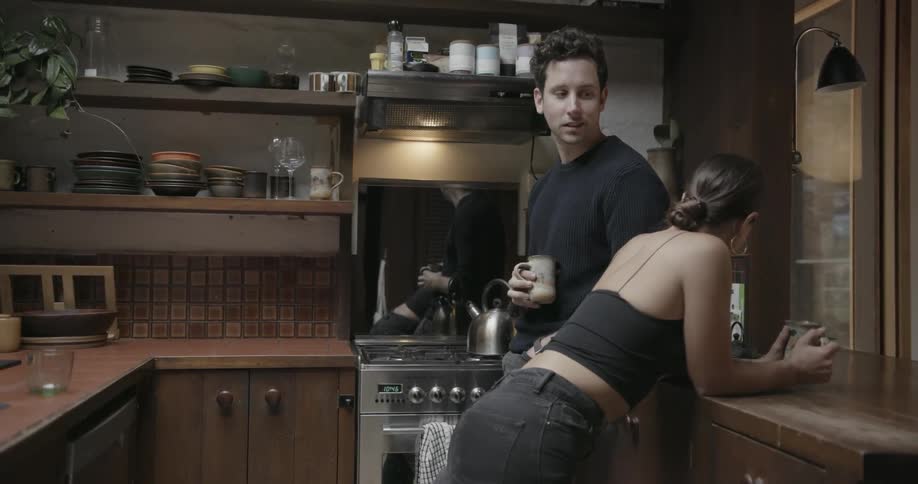 A man and a woman are having a casual conversation in the kitchen