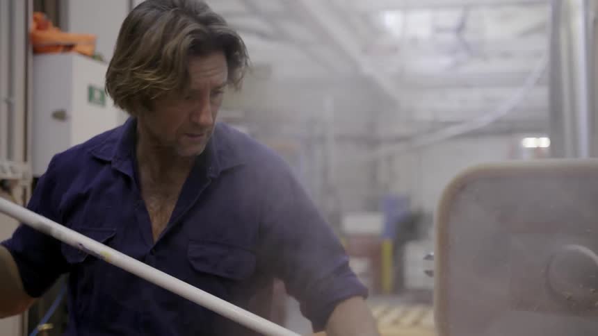 A man scrapes steaming things into a square container