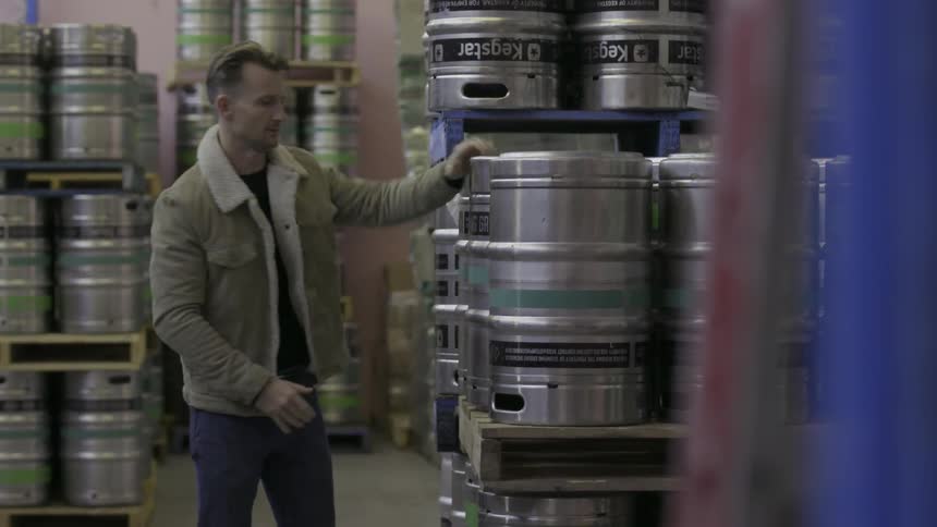 Man sets down a barrel and then picks up the one next to it