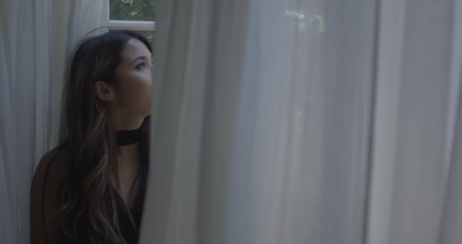 Woman sitting on the edge of a window looking out