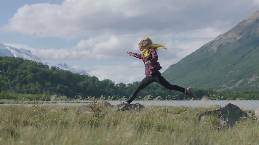 A woman leaps over the grass in a meadow