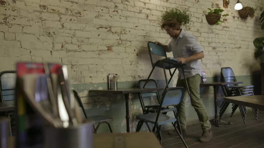 Man unstacks chairs and set them by tables