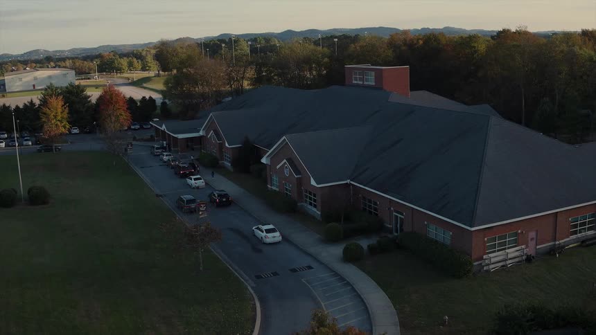Cars drive and make a turn in front of a building