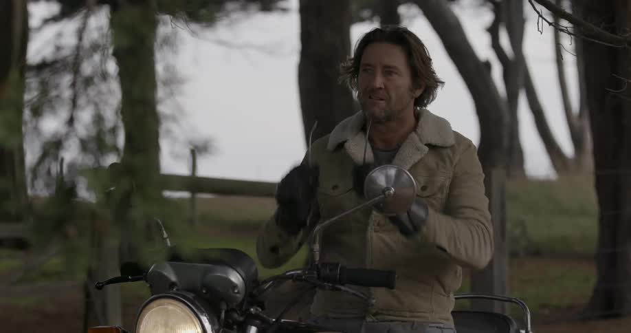 A man on a motorcycle puts on his sunglasses