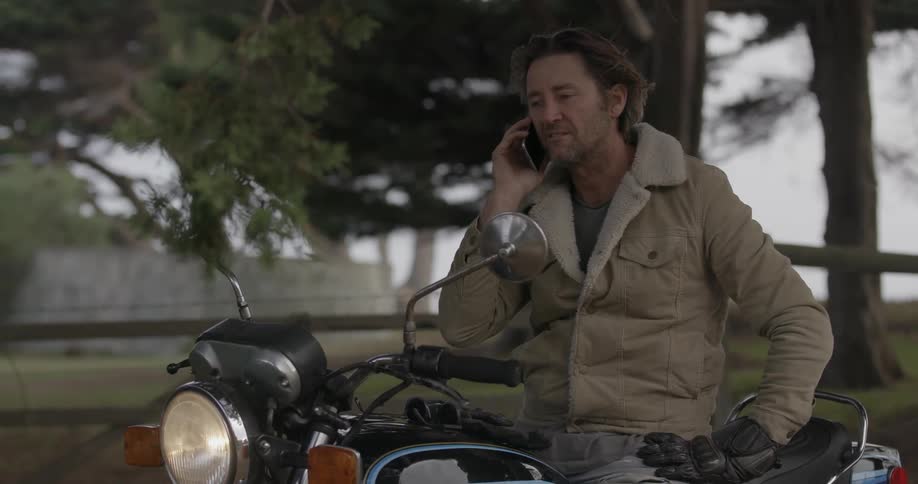 Man sitting on his motorcycle talking on his cell phone