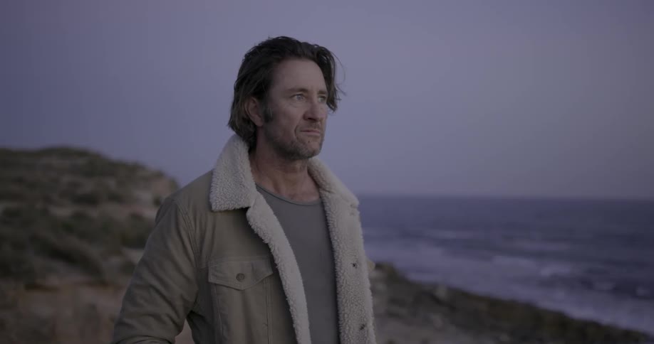 A man stands on a beach at sunset