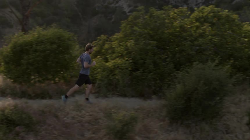 A man jogs in the mountains on a sunny day