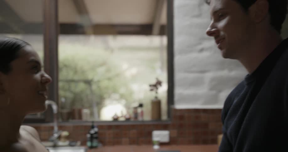 A man is standing in the kitchen talking with a woman
