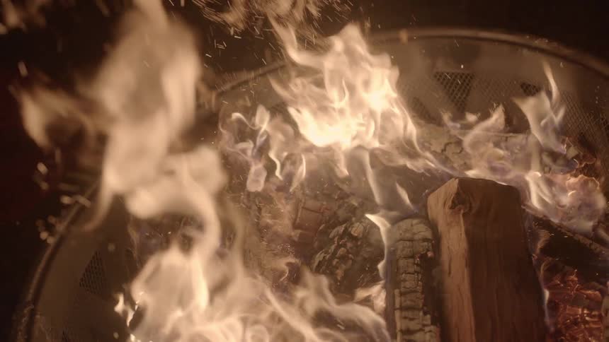 A man steps on a piece of wood on a bonfire