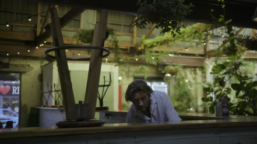 A man puts barstools on the ground inside a restaurant