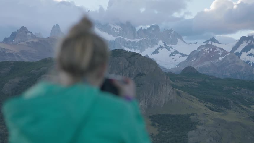 Woman takes pictures of snowy mountains