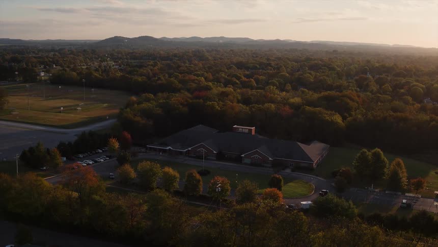 A large house sits in the forest below