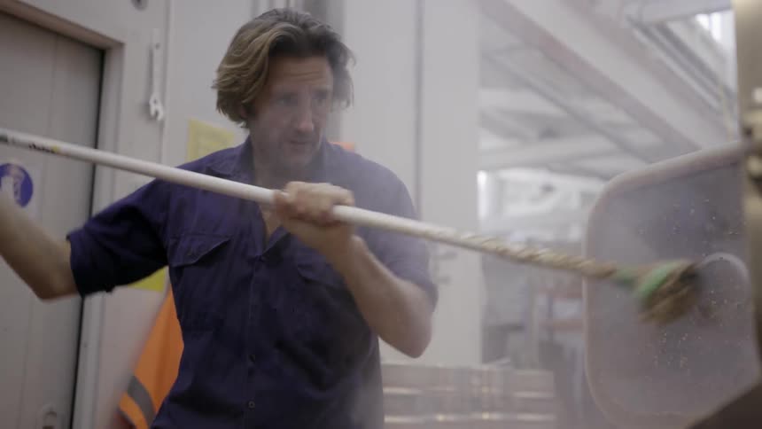 A man is mixing something with a long stick