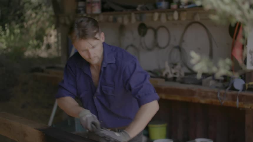A carpenter smooths a wood beam