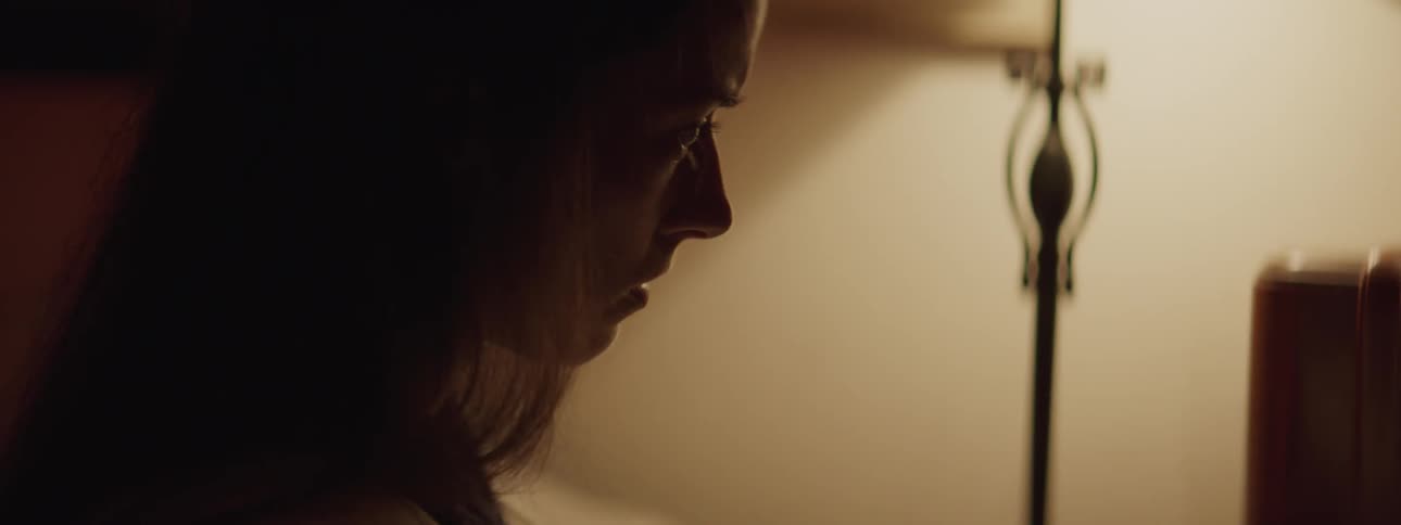 A woman in her bedroom is taking off her necklace