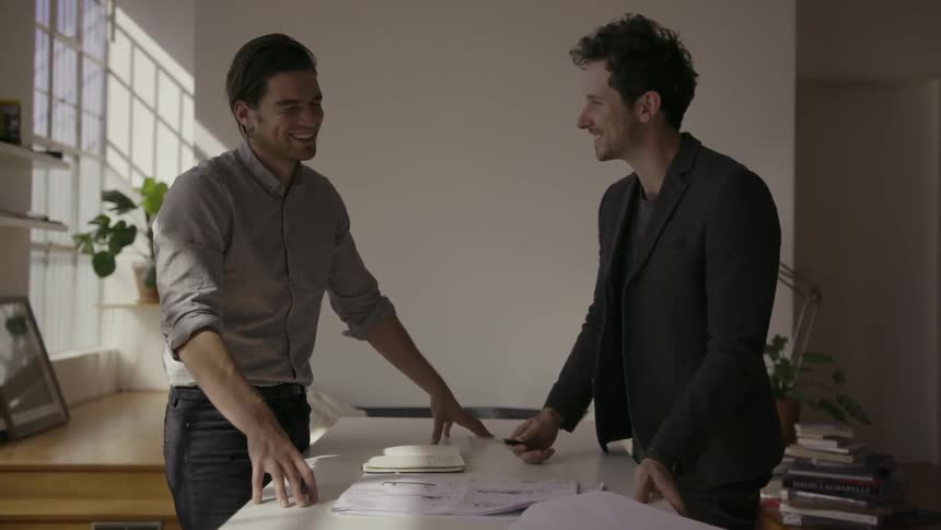 Two men are looking and discussing paperwork in an office building