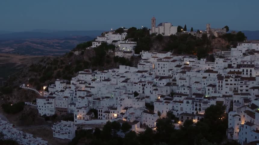 A city built on a large hill is being filmed at dusk