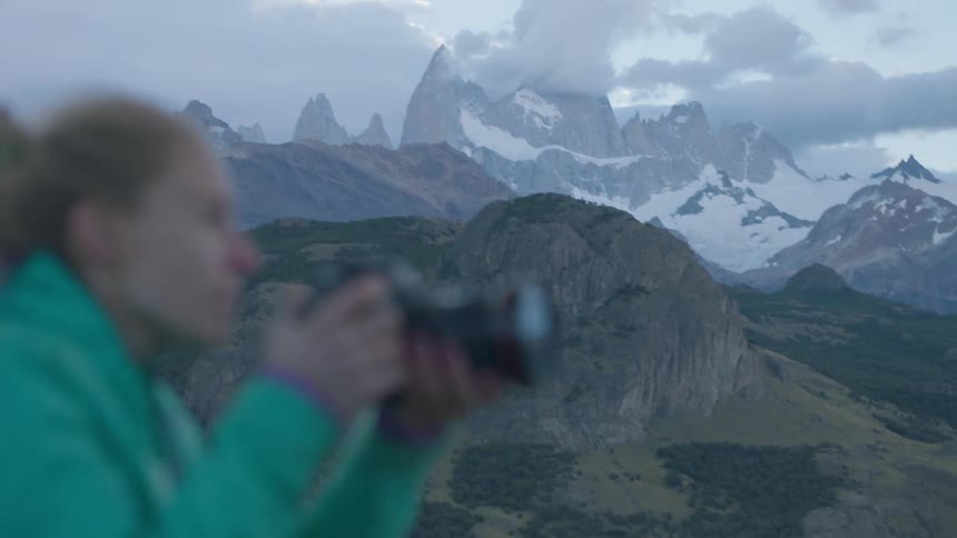 Woman takes pictures of snowy mountains