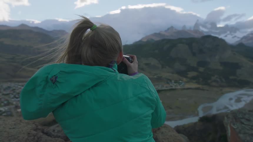 Woman taking pictures of a mountainous landscape