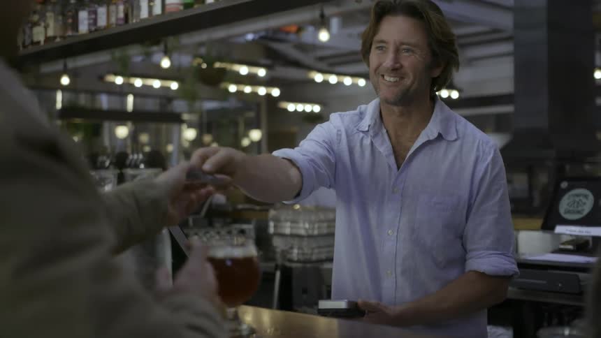 A bartender takes a credit card payment