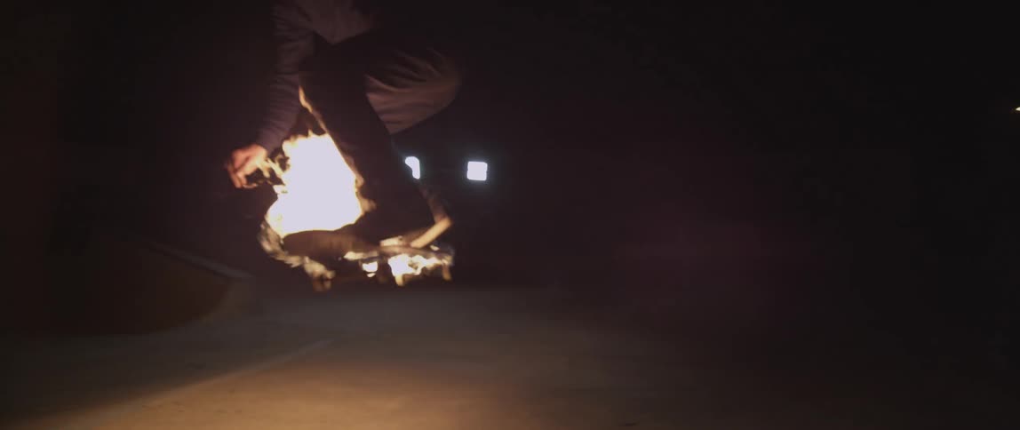 Person rides on a skateboard lit on fire at night