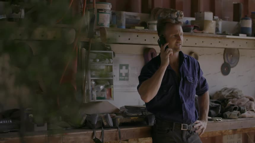 A man stands in the shed talking on his phone