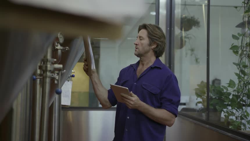 Man looks at a clipboard and types into a tablet