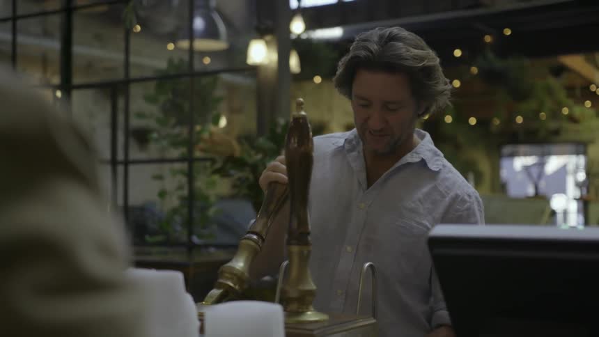 A bartender hands a customer their drink