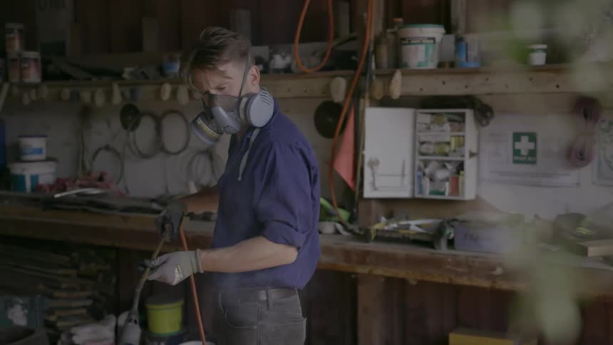 A man wearing a safety mask is using a blow torch