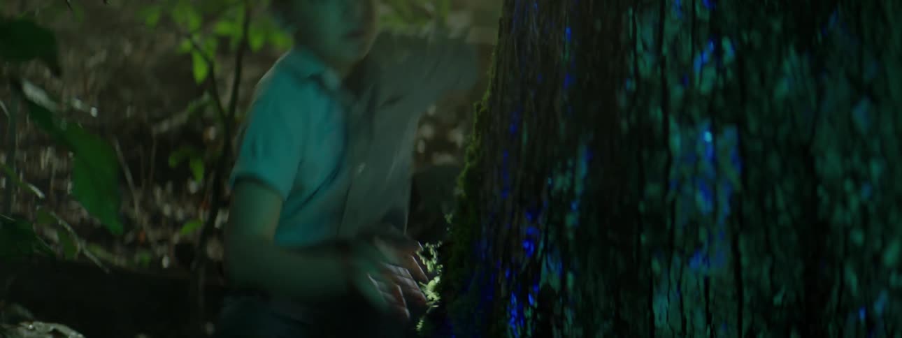 A boy startles away from a tree that is glowing blue