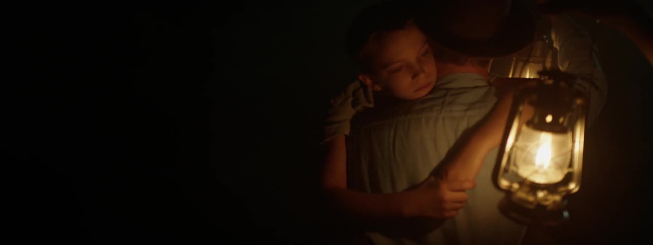 A young boy is being held by his father and two people are holding lanterns