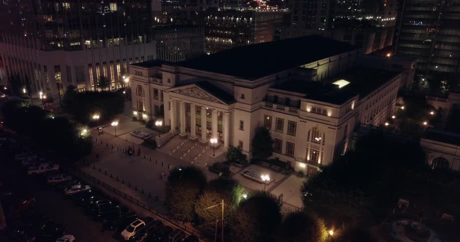 A large building is lined with people out front