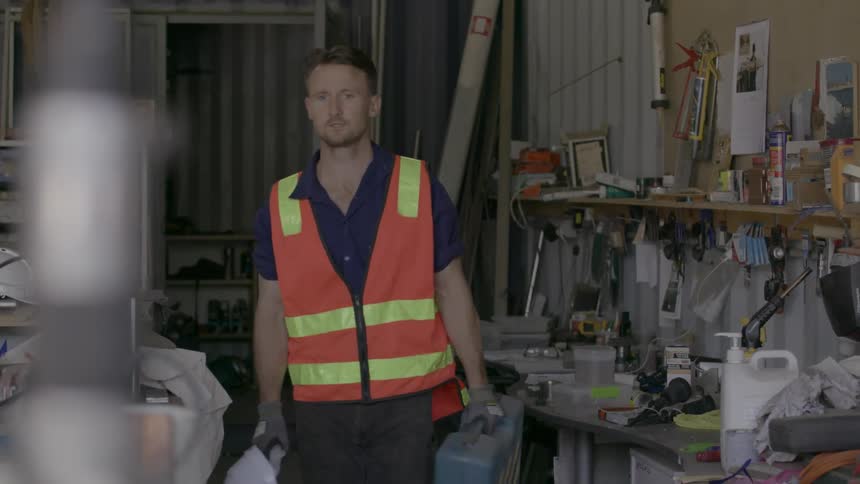 Man wearing a safety vest picks up a tool case