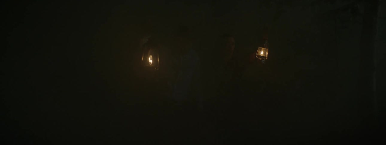 A man and woman hold lanterns aloft as they walk