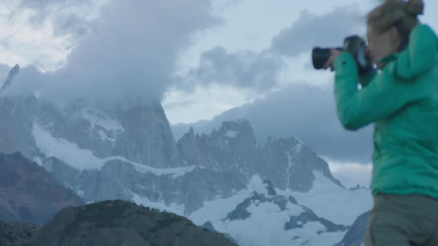 A woman takes photographs from a mountain top