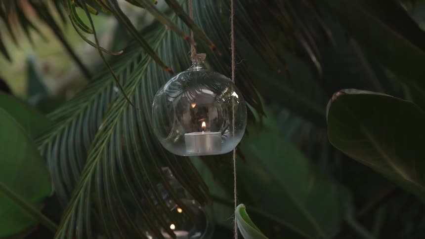 A votive candle hangs inside a glass bulb