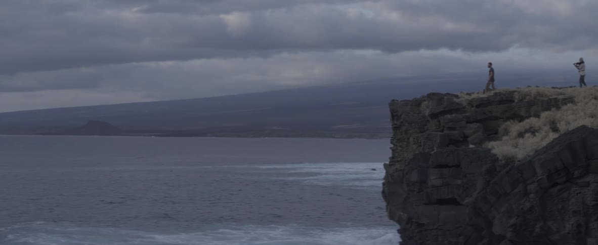 A man approaches a cliff edge overlooking the ocean