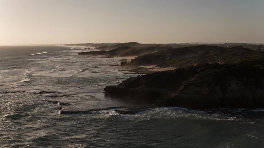 An aerial shot of waves crashing along the shoreline