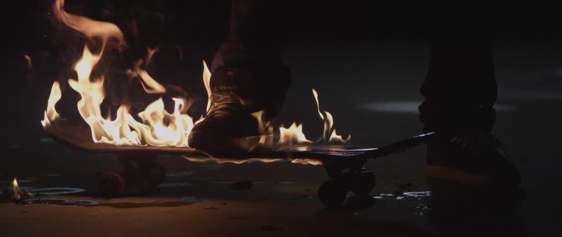 A person stamps his foot down on a burning skateboard