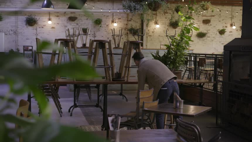 A man puts chairs down in a restaurant