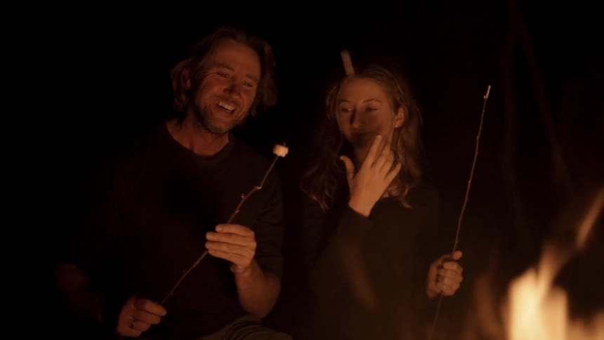 A man and a girl are roasting marshmallows on a stick next to a fire