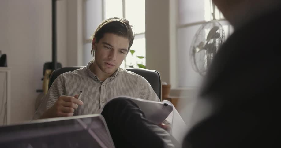 Two people talk together while looking at papers