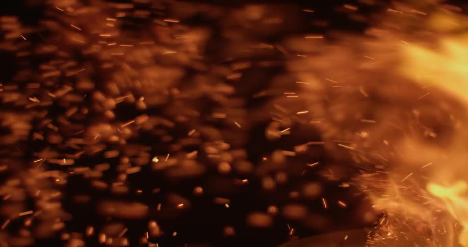 Fire blazes and sparks fly up in the dark