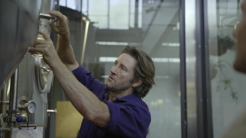Man pours a glass of beer out of a large drum