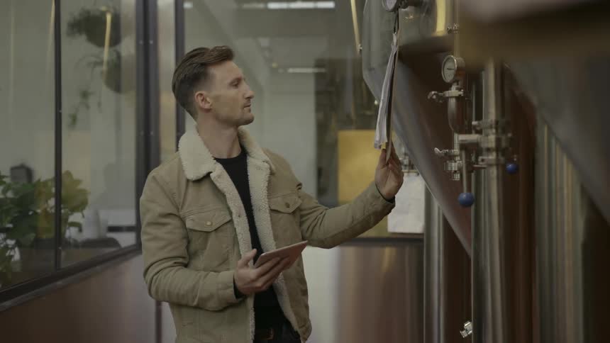 A man walks through a distillery checking clipboards