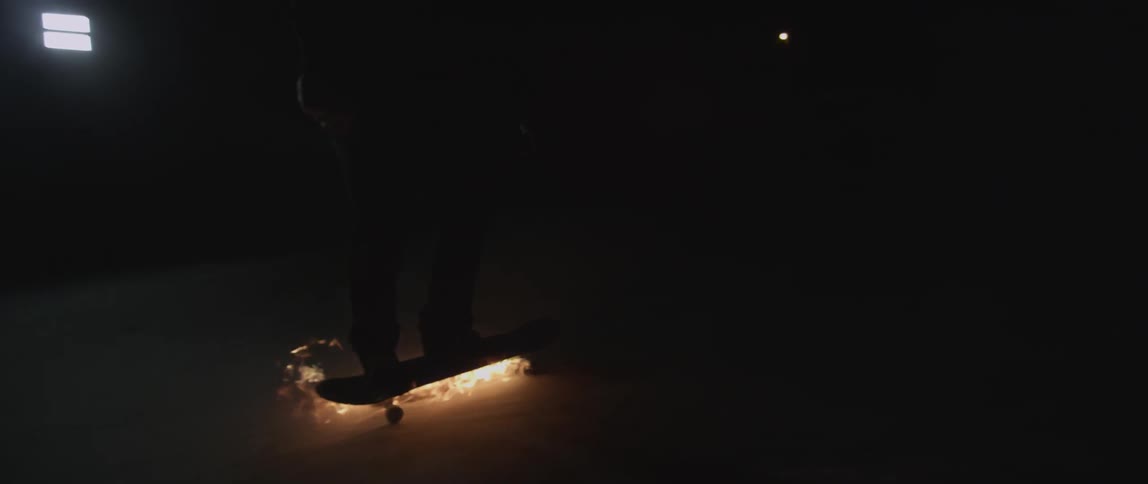 Person rides on a skateboard lit on fire at night