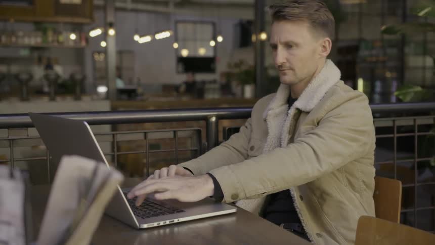 A man uses his laptop in a cafe