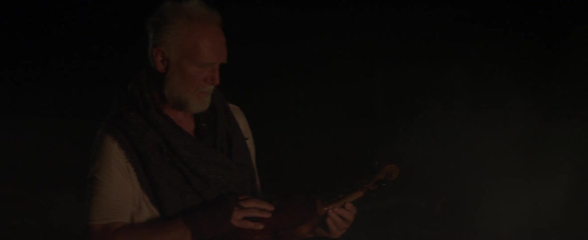 A man is inspecting a violin in the dark