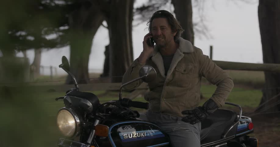 A man sits on a motorcycle talking on his phone